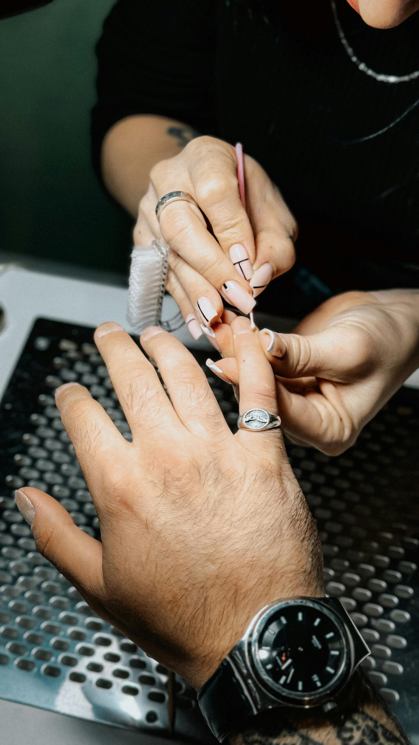 Close-up of a nail artist painting manicure on a client's hand in a salon setting.